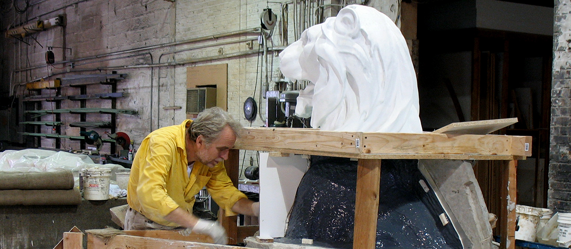 Man working on lion statue in shop